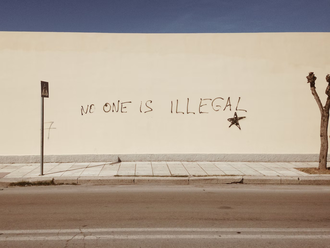 Muro con graffiti 'No one is illegal'
